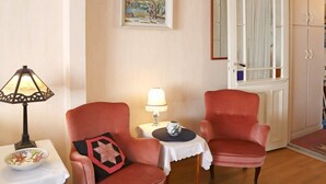 A room with two armchairs, a small table with a lamp, a framed painting, and a wardrobe. - 5 Person Holiday Home in Risor (Risør)
