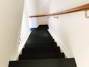 Una escalera con escalones negros y barandilla de madera.