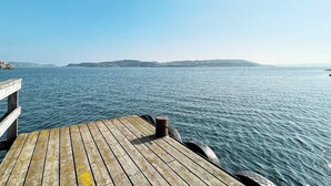 Eine Holzstege, der sich in ruhiges Wasser erstreckt, mit wolkenlosem Himmel darüber.