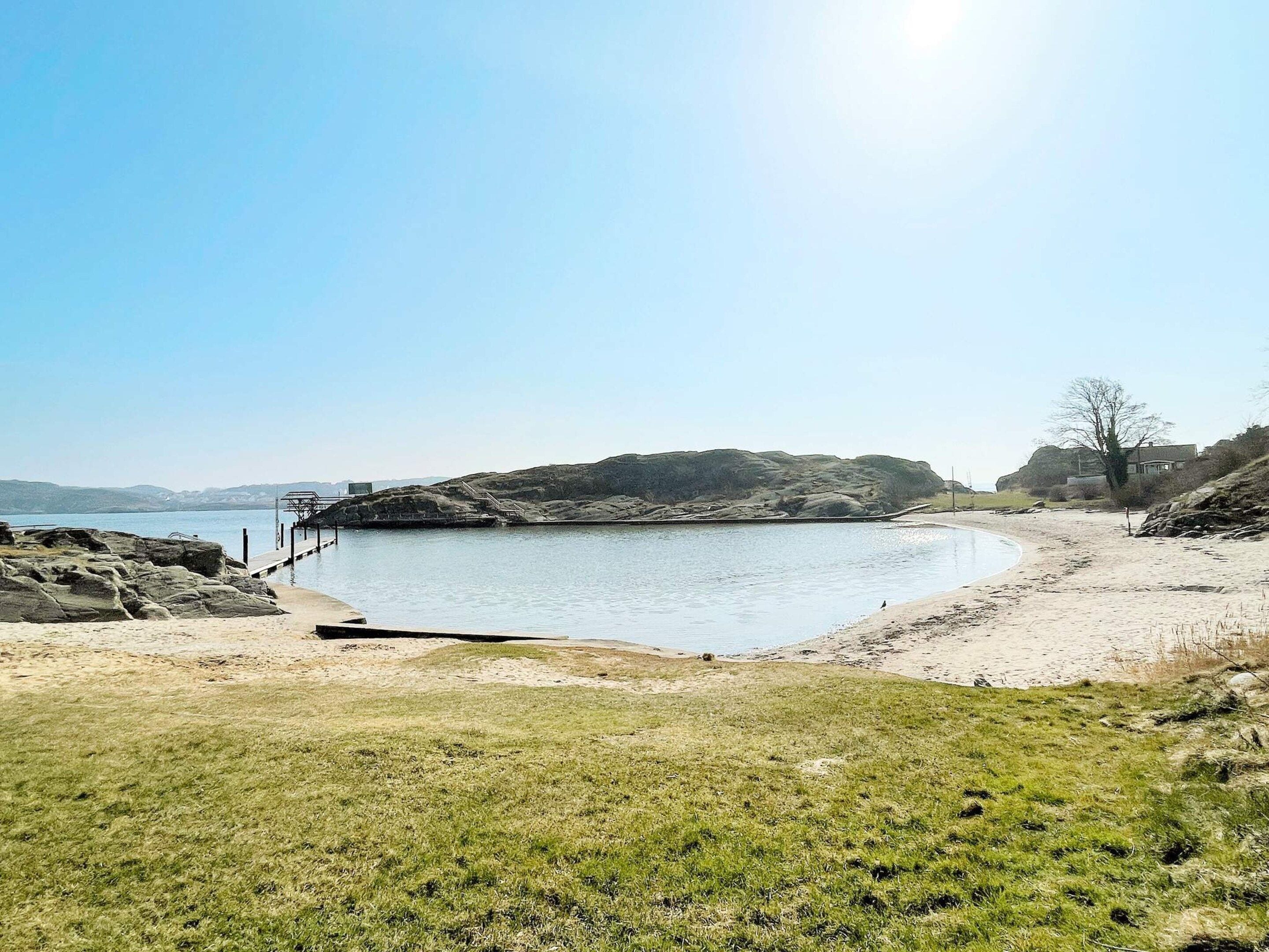Une plage avec un rivage rocheux, une jetée et une zone herbeuse.