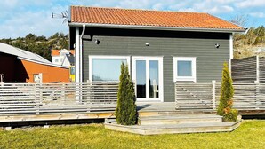 Ein modernes, zweistöckiges Haus mit grauem Putz und einem roten Ziegeldach.