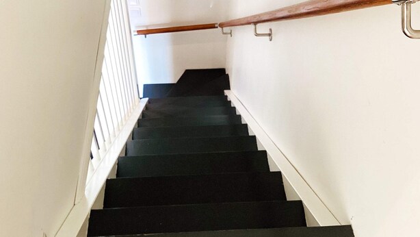 Eine Treppe mit hölzernem und Metallgeländer, die zu einer oberen Etage führt.
