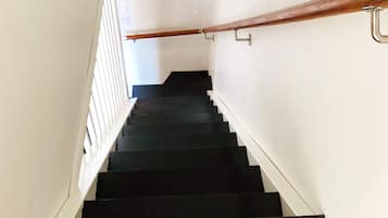 A staircase with a wooden handrail and metal handrails, leading to an upper floor.