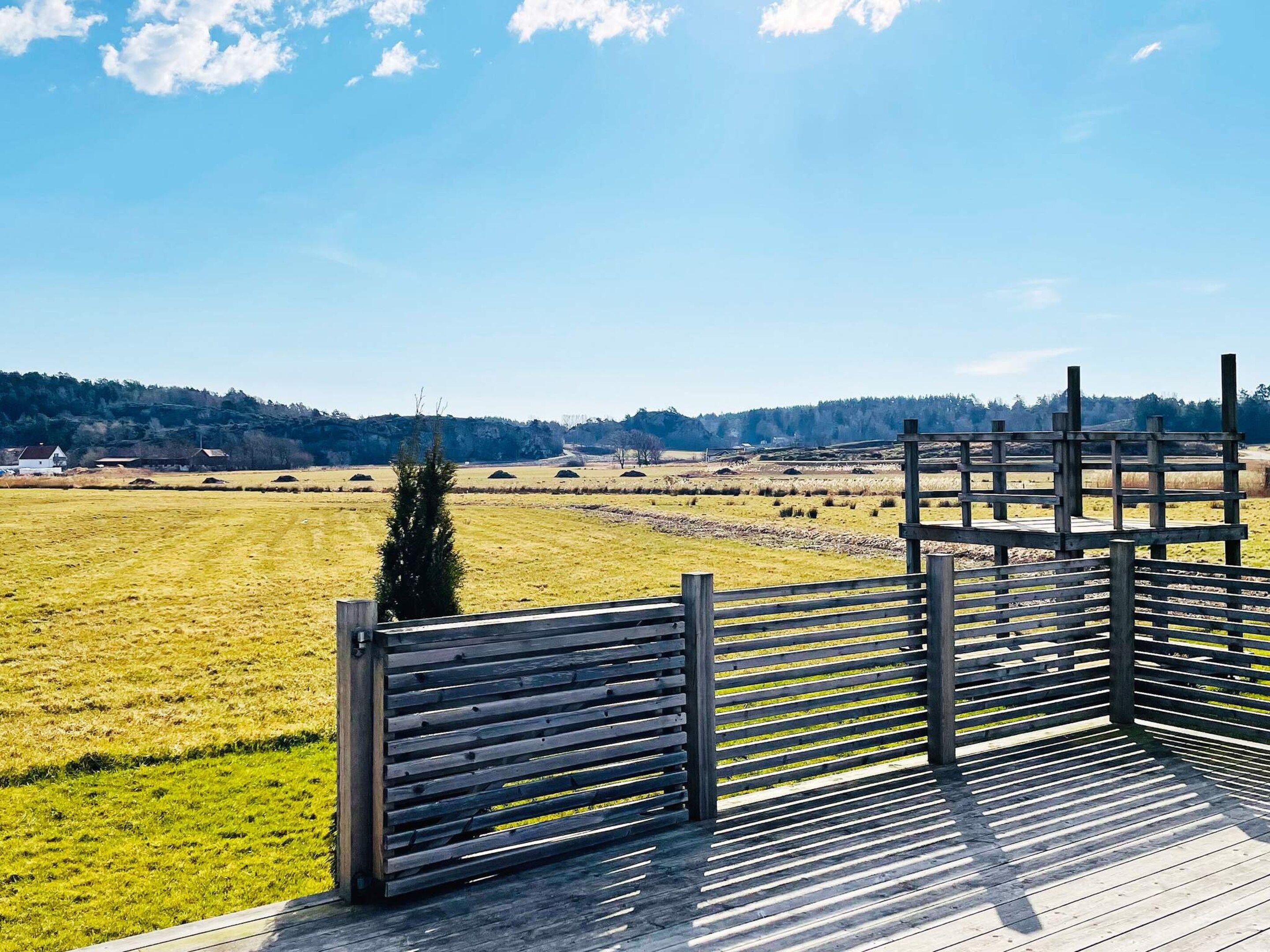 A wooden deck with a view of a rural landscape, including fields and distant buildings.