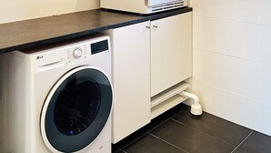 Ein kleiner Waschbereich mit Waschmaschine, Schrank und Arbeitsplatte.