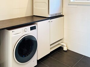 Een kleine wasruimte met een wasmachine, een kast en een werkblad.