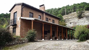 A two-story brick house with a covered porch and a stone wall.