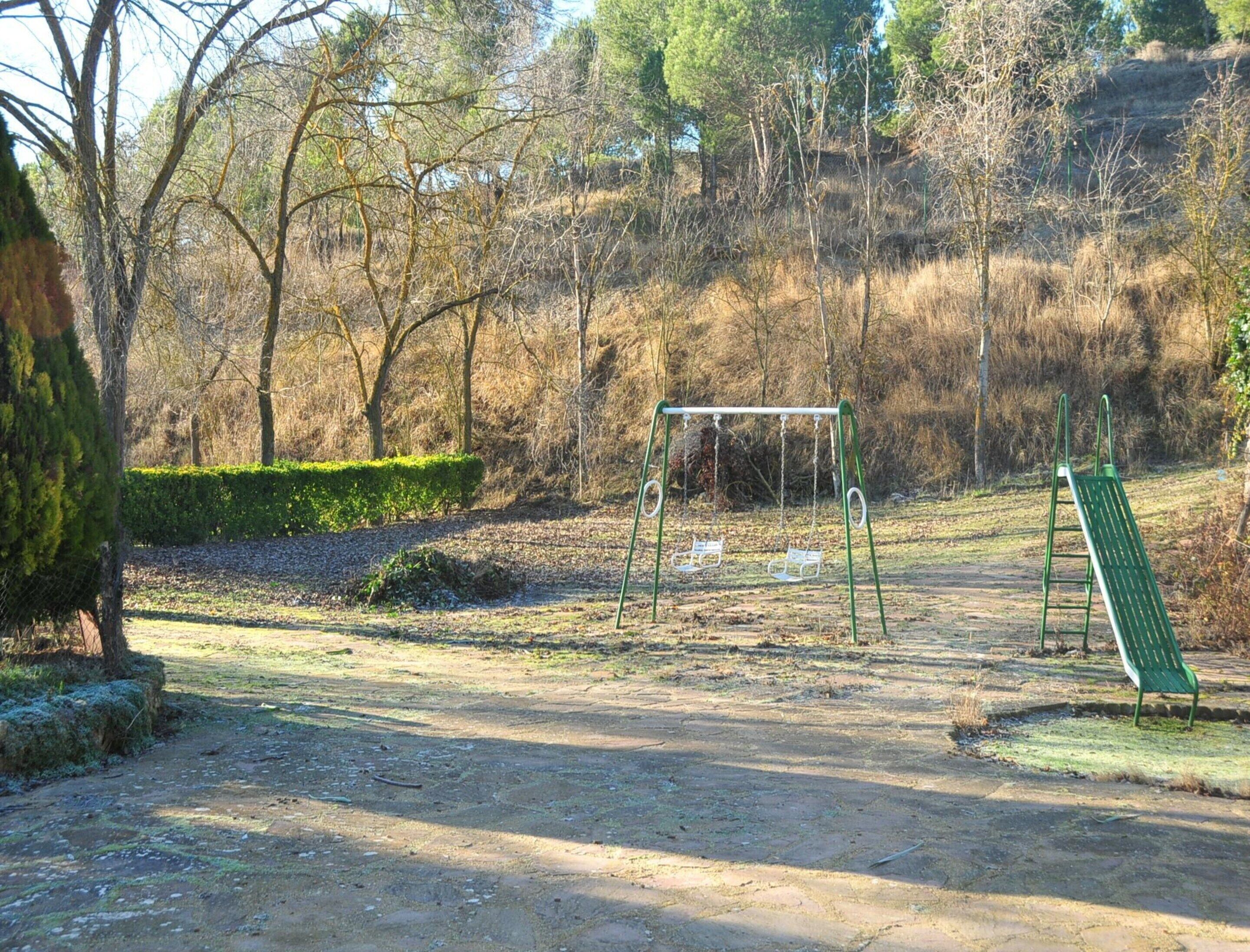 A park with a swing set, a green bench, and a dirt path.