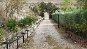A gravel path flanked by stone walls and greenery, leading to a distant view.