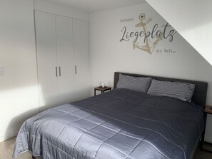 A bedroom with a bed, a nightstand, a wardrobe, and a wall decoration. - Huus Rehders Modern Retreat (Büsum)