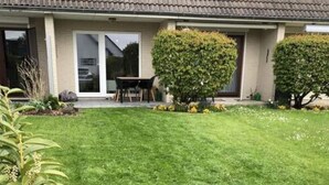 A residential property with a well-maintained lawn, a patio with outdoor furniture, and various shrubs and flowers. - Huus Rehders Modern Retreat (Büsum)