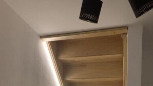 A modern staircase with wooden steps and a black handrail, leading to a landing with recessed lighting. - Huus Rehders Modern Retreat (Büsum)
