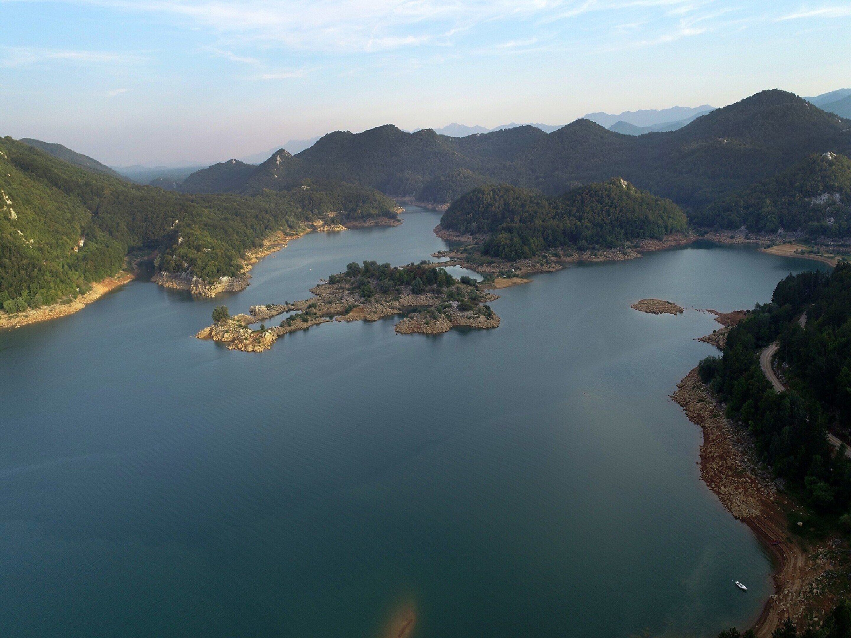 A large body of water surrounded by forested hills.