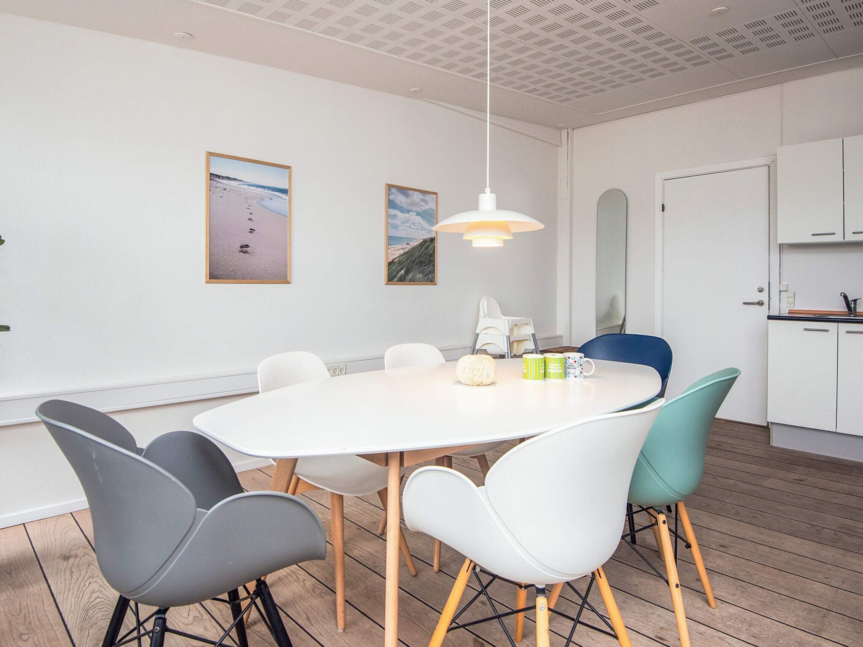 Un'area pranzo moderna con un tavolo rotondo, sedie e una lampada a sospensione.