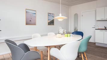 Un'area pranzo moderna con un tavolo rotondo, sedie e una lampada a sospensione.