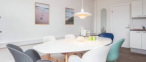 A modern dining area with a round table, chairs, and a hanging light fixture.