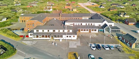 A large building with multiple parking spaces and a road leading to it.