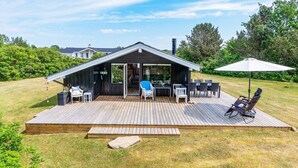 Una casa moderna con terraza, asientos exteriores y un gran paraguas.