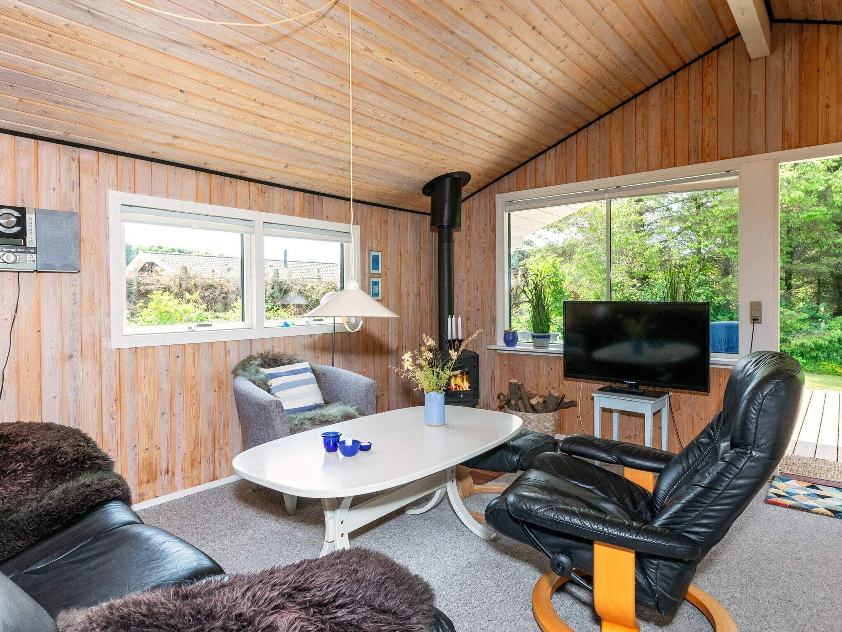 A cozy room with wooden walls, a fireplace, a television, and comfortable seating.