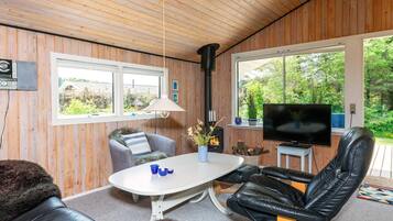 A cozy room with wooden walls, a fireplace, a television, and comfortable seating.