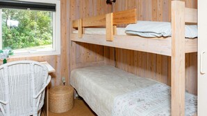 A bunk bed room with a window, a wicker chair, and a small table. - 4 Person Holiday Home in Hjorring (Hjørring)