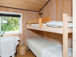 A bunk bed room with a window, a wicker chair, and a small table. - 4 Person Holiday Home in Hjorring (Hjørring)