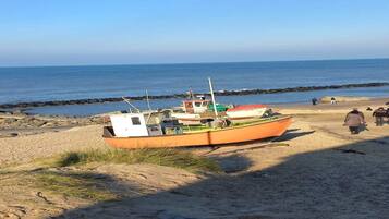 A boat on a sandy beach with the ocean in the background.