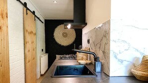 Cozinha moderna com ilha central, parede preta e tapete circular, além de backsplash de mármore.