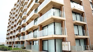 A multi-story residential building with balconies, large windows, and a brick facade. - Apartment in Nieuwpoort Near the Beach (Nieuwpoort)