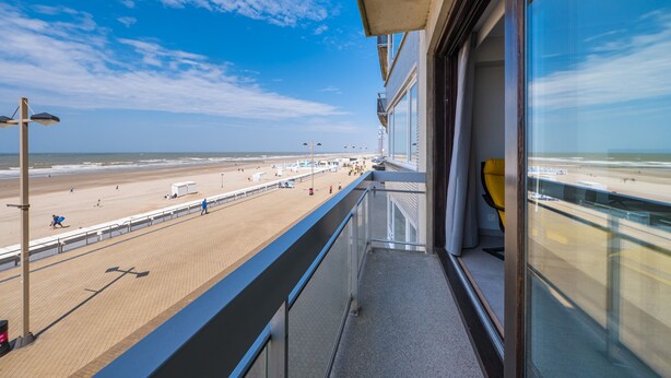 A balcony with a view of a beach and ocean.