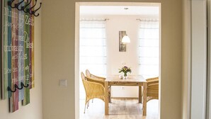 A hallway leading to a dining area with wicker chairs and a table, a wall-mounted art piece, and a window with curtains. - Apartment in Oberkirch (Oberkirch)
