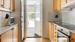 Une cuisine moderne avec des meubles en bois, un four à micro-ondes encastré, un évier en acier inoxydable et une grande fenêtre.