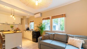 Un espace de vie moderne comprenant un canapé, une table basse et une cuisine avec des meubles blancs et un îlot central.