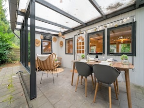 A covered patio with a table set for dining, wicker chairs, and a wicker sofa. - Holiday Home in Gelderland Near Woodlands (Hattemerbroek)