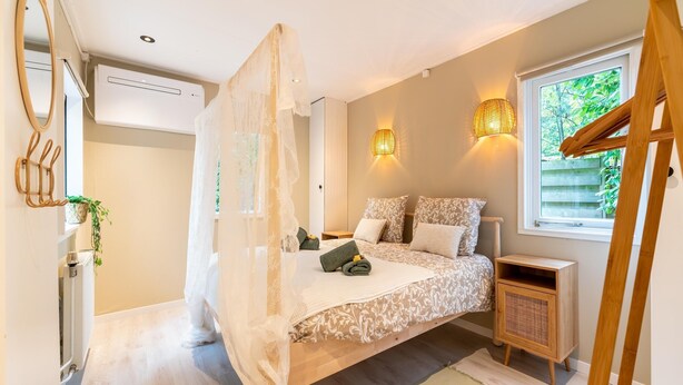 Une chambre à coucher avec un lit à baldaquin, des lampes de chevet, une fenêtre donnant sur un beau paysage et une table de chevet en bois.