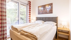 A double bed with a grey headboard, a wooden bedside table with a lamp, and a painting of hearts on the wall. - Amazing Chalet With Terrace (Stadl-Predlitz)