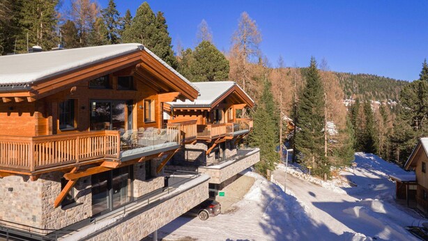 A wooden cabin with a stone foundation, a balcony, and a view of a snowy mountain. - Amazing Chalet With Terrace (Stadl-Predlitz)