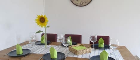 A dining table set with green napkins, wine glasses, and a sunflower centerpiece.