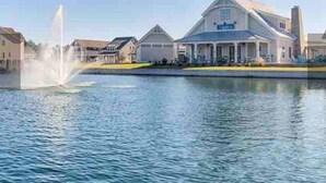 A waterfront property with a large house, a fountain, and a calm body of water. - Resort style, beach town cottage, 5 mins from the beach- family friendly. (Beaufort)