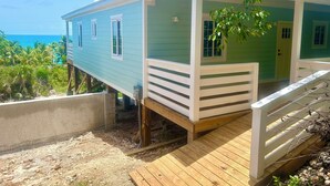 A two-story house with a wooden deck and a view of the ocean. - Sunset Escape: A Secluded Hideaway  (Rainbow Bay,  Eleuthera)
