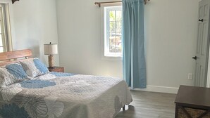 A bedroom with a bed, a ceiling fan, a window with curtains, and a door. - Sunset Escape: A Secluded Hideaway  (Rainbow Bay,  Eleuthera)