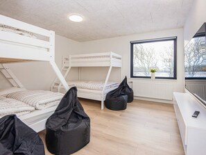 A bunk bed room with a window, a radiator, and a desk with a remote control. - 4 Star Holiday Home in Ulfborg (Ulfborg)