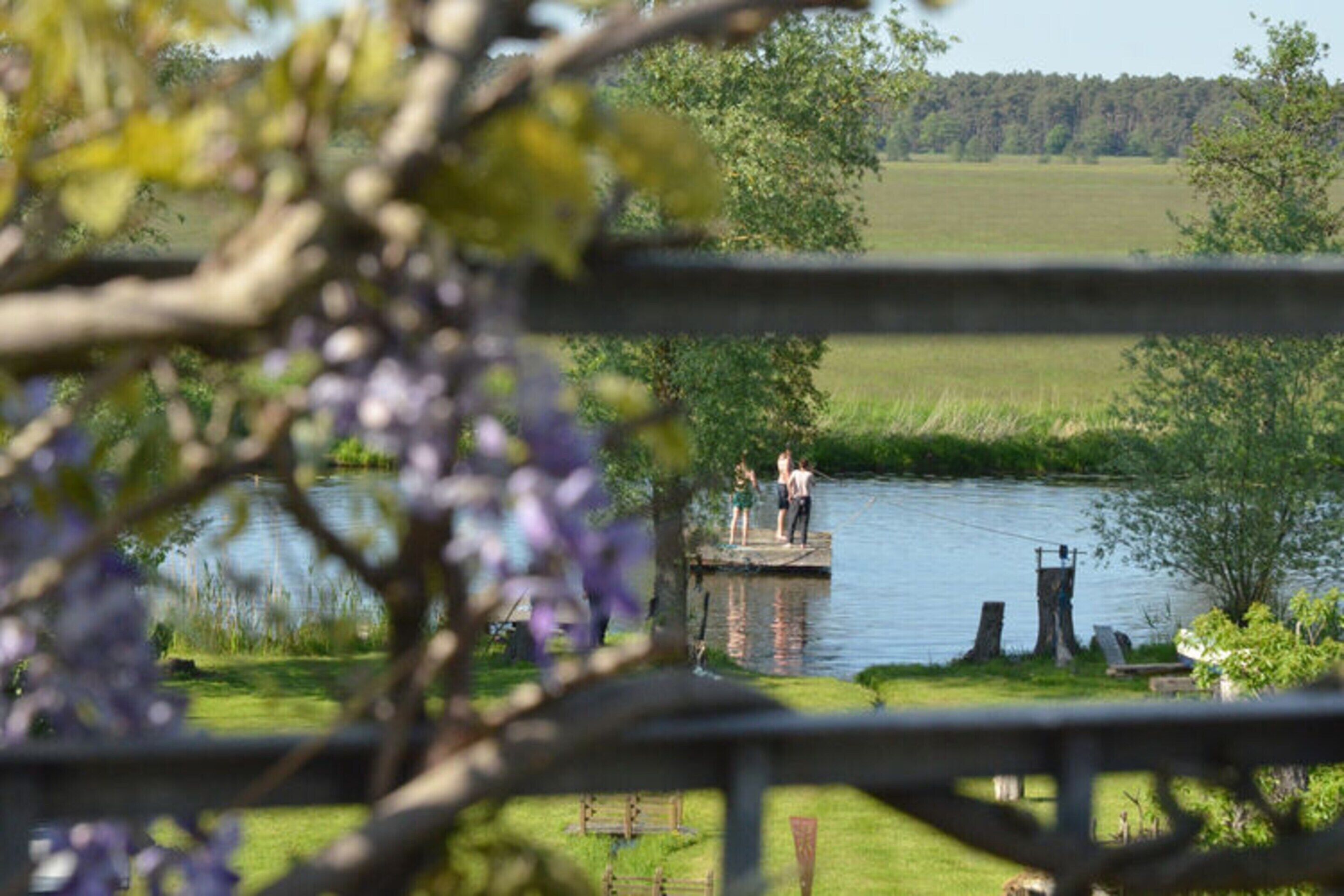 A view of a lake with a dock and people standing on it.