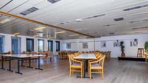 A spacious conference room with multiple tables and chairs, large windows, and artwork on the walls. - 4 Person Holiday Home on Holiday Park in Glesborg (Glesborg)