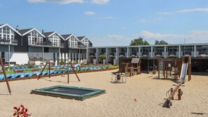 A beach area with a pool, lounge chairs, a slide, and a wooden play structure. - 4 Person Holiday Home on Holiday Park in Glesborg (Glesborg)