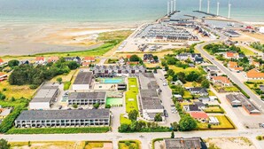 An aerial view of a coastal town with a marina, wind turbines, and residential areas. - 4 Person Holiday Home on Holiday Park in Glesborg (Glesborg)