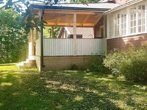 Une maison en bois avec un porche, un petit jardin devant et une fenêtre bien visible.