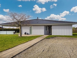 A modern single-story building with a tiled roof, a covered porch, and a gravel driveway.