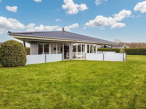A modern house with a covered patio, large windows, and a well-maintained lawn. - 4 Star Holiday Home in Sydals (Sydals)