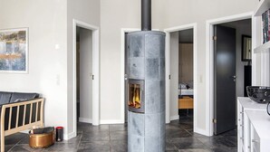 A modern interior with a central stone fireplace, a wooden bench, and a bookshelf. - 4 Star Holiday Home in Sydals (Sydals)